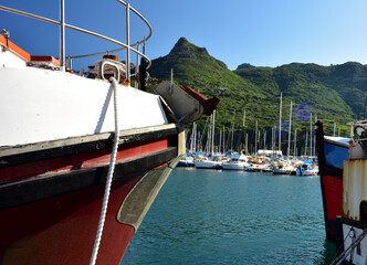 Looking at splendid yachts between the bows of two old vessels  in Hout Bay harbor on a sunny day