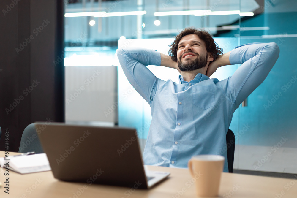 Poster taking break. smiling middle aged man relaxing on chair, sitting at table and resting, using pc lapt