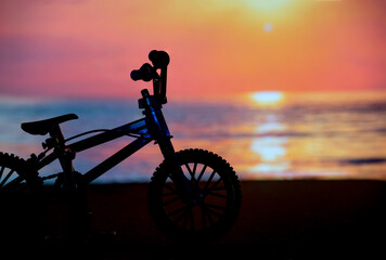 Fototapeta na wymiar The silhouette photo of bicycle on the beach with sunset twilight hour background