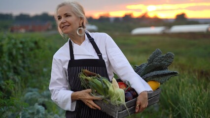Extreme closeup of female chef carrying vegetables on her hip and smiling and waving to someone...