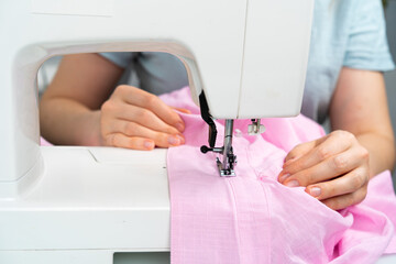 Obraz na płótnie Canvas women's hands sew on a sewing machine, light photo, work at home, handmade