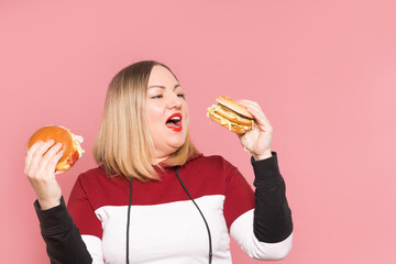 Cheerful woman with appetite looks at a delicious burger. . Unhealthy food.