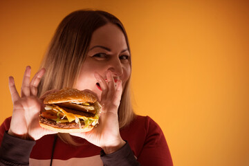 A hungry woman is biting a big tasty burger