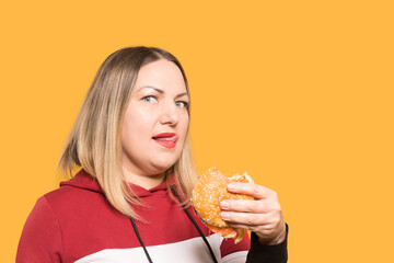 A hungry woman is biting a big tasty burger