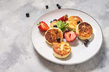 Cottage cheese pancakes, ricotta fritters or syrniki with currant and strawberries. Healthy and delicious breakfast.