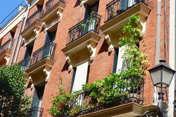 Elegant balconies with greenery on the retro building downtown Madrid, Spain