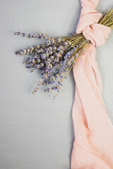 A bouquet of dried lavender and a chiffon scarf on a gray background. Flat lay, vertical image.