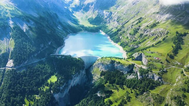 Water dam and reservoir lake aerial drone footage in green Swiss Alps mountains generating hydroelectricity. Low CO2 footprint, decarbonize, renewable energy, sustainable development. 4K 60fps video.