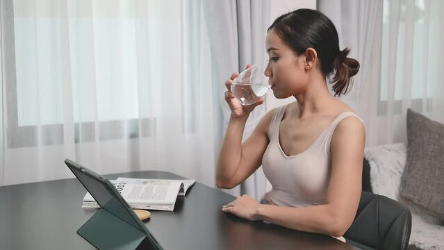 Girl smiling with water and phone after exercising at home