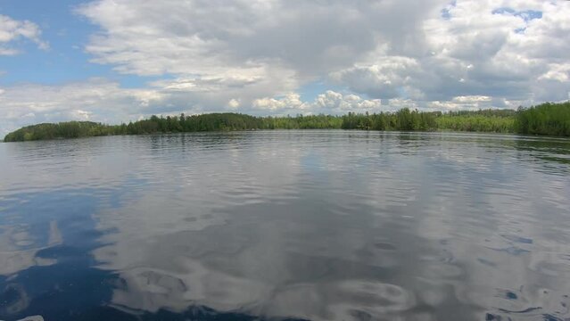 POV from fishing boat while cruising over open waters of flooded Lake Vermilion in northern Minnesota; low angle; passing by island and shore; concepts of fishing, boating, and vacation