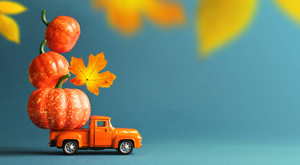 Retro truck with pumpkins and leaves on blue background. Concept of Thanksgiving day, Halloween and...