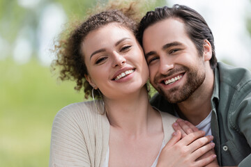 portrait of pleased woman and happy bearded man looking at camera.