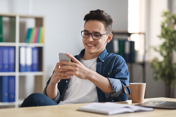 New App. Smiling Young Businessman Relaxing With Laptop At Workplace In Office