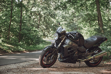 Black road bike in the forest on the roadside of the asphalt road, no people