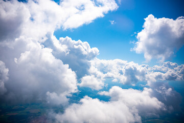 Obraz premium Aerial view scene of rural place which hiding under white fluffy clouds and blue bright sky background.