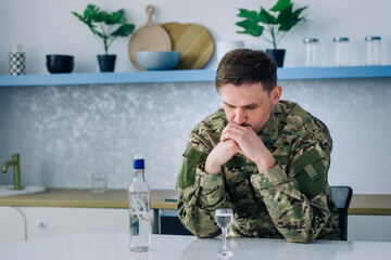Upset male soldier drinking bottled alcoholic beverage at home a