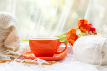 Coffee morning.  Yellow steaming cup of hot coffee for relax after working hobbies crochet on white wooden near window with flowers