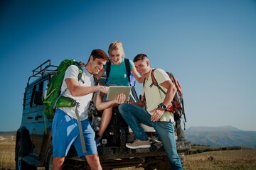 Team of hiking people using internet and tablet computer pc guide book