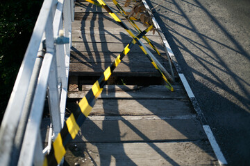 Metal fence in wooden bridge. Caution tape black and yellow line striped in wooden bridge