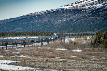 Long pipeline passing through a field with mountains and trees in the background