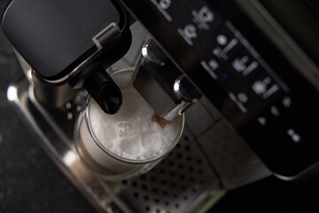 Freshly brewed latte is poured from the coffee machine into glass cups.