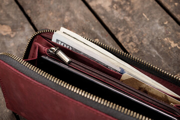 Leather red wallet with money and credit cards on old wooden background