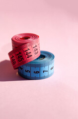 Pink and blue centimeter tapes on a pink background. - 516344415