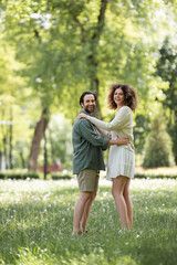 Naklejka na ściany i meble full length of joyful young couple having date in green summer park.