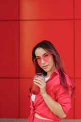 Young beautiful woman with pink hair on a bright background with lemonade