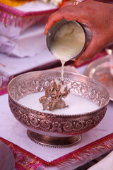 Puja in a Hindu temple : bathing of a statue of goddess Durga with semolina