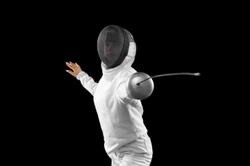 Energetic female fencer in white fencing costume and mask in action, motion isolated on dark...