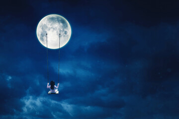 Little girl sit on the swing while hanging on moon