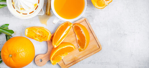 Homemade squeezed orange juice and fresh oranges fruits on a white wooden background. Cut the orange fruit in half to make orange juice.