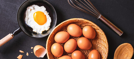 Menu cooking in kitchen egg fried egg in the pan  and fresh eggs in baskets on black wooden background