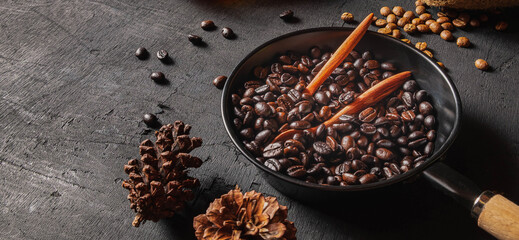 Traditional roasted arabica coffee beans and brown coffee bean in a pan on a black wooden background