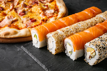 set of pizza and sushi rolls on a dark stone background