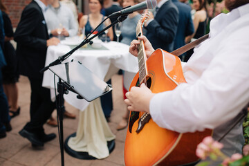 musician playing the guitar. Singer sings on the guitar outside at a wedding. Wedding with live...
