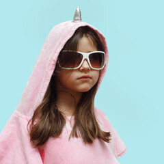 little girl in a pink poncho and sunglasses very serious, funny child in a unicorn costume isolated...