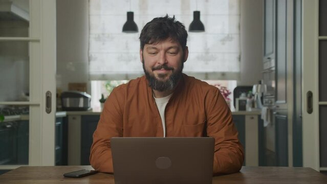 Happy caucasian bearded guy working on the laptop computer 