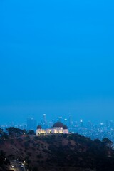 Vertical shot of the Griffith Observatory on a hill in Los Angeles, California against a blue sky