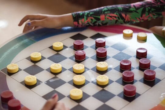 Closeup of two women playing checkers with bottle caps from alcoholic beverages
