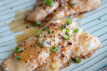 Caramelized catfish filets with chopped green onions and crushed red peppers