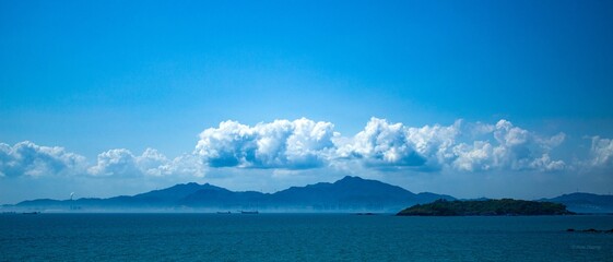 Breathtaking view of the blue cloudy sky and the Daya Bay merging into silhouettes of mountains