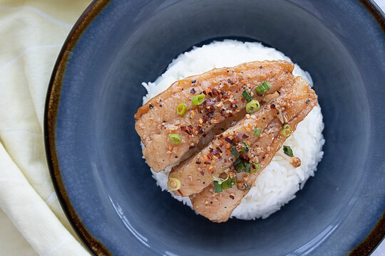 A caramelized catfish filet with Jasmine rice and crushed red peppers with chopped green onions