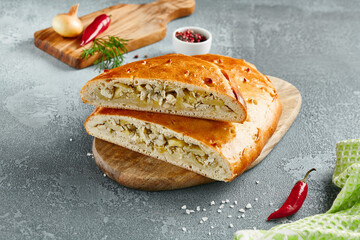 Classic chicken and potato pie on wooden board with ingredients. Composition with chicken pie on concrete background with textile and spices. Homemade pie with turkey and potato in rustic style.