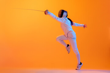 Fototapeta na wymiar Studio shot of professional fencer in white fencing costume and mask in action, motion isolated on orange color background. Sport, youth, activity, skills,