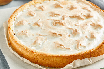 Sweet bakery - lemon tart with meringue on gray stone background. Lemon pie with mousse in rustic style on stone table. Aesthetic composition with lemon tart. Citrus tart with meringue.