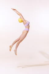 Portrait of young woman in swimming suit and cap jumping into water isolated over grey studio background. Fly jump