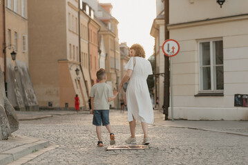 A family is strolling on the paving stones in an old European town. A happy mother and son are...