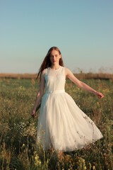 Fototapeta na wymiar Romantic woman dancing in a wonderful flower field. Warm sunset colors